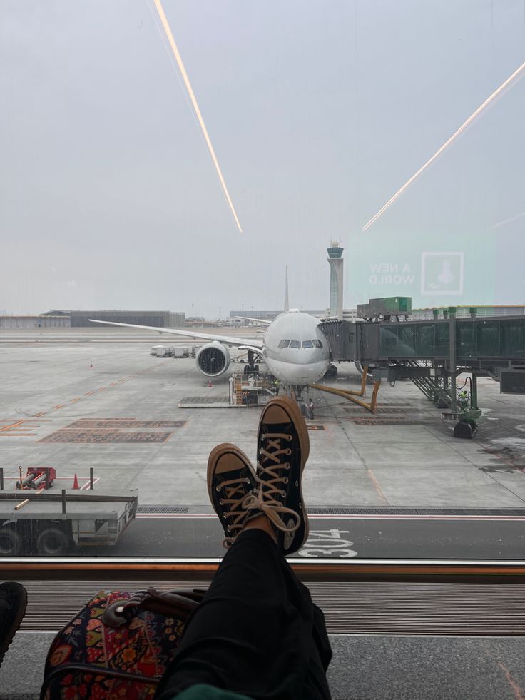 a person's feet on the window sill at an airport