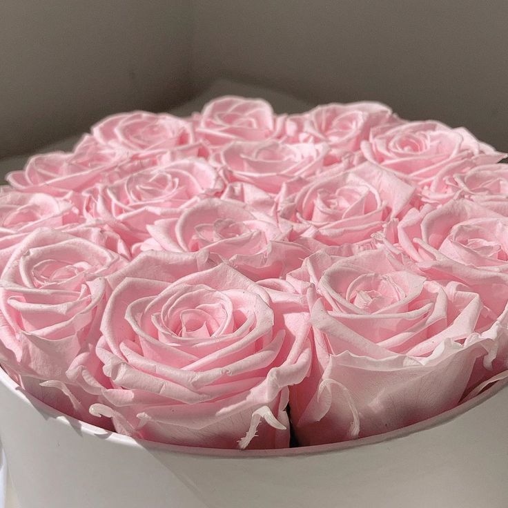 a white box filled with pink roses on top of a table