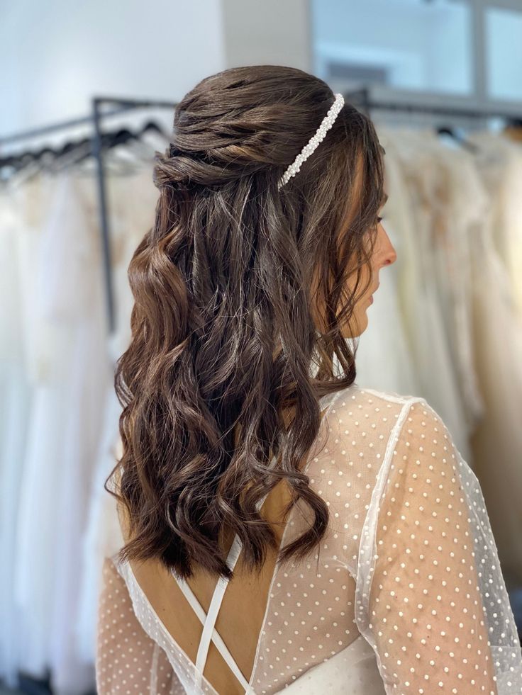 a woman standing in front of a rack of dresses with her hair pulled back and wearing a headband