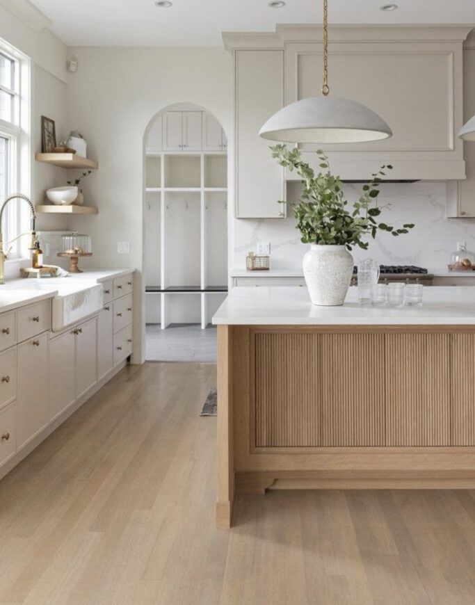 a large kitchen with white cabinets and wood flooring on the countertops, along with an island in the middle