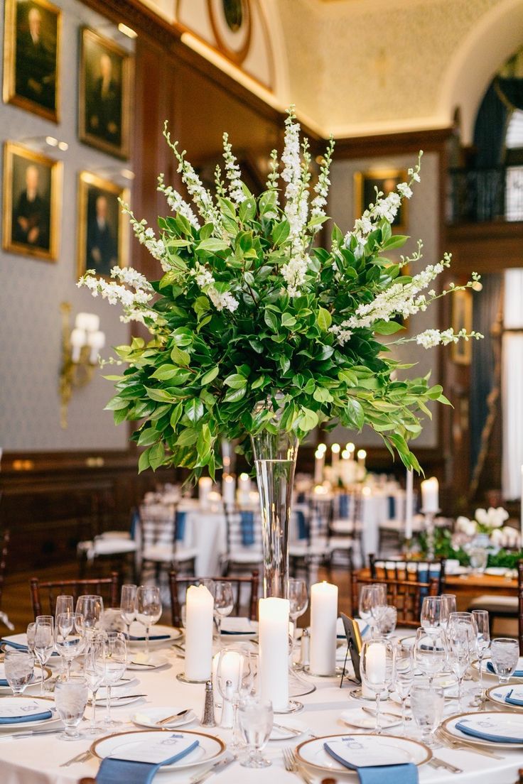 there is a vase with flowers and candles on the dining room table set for dinner