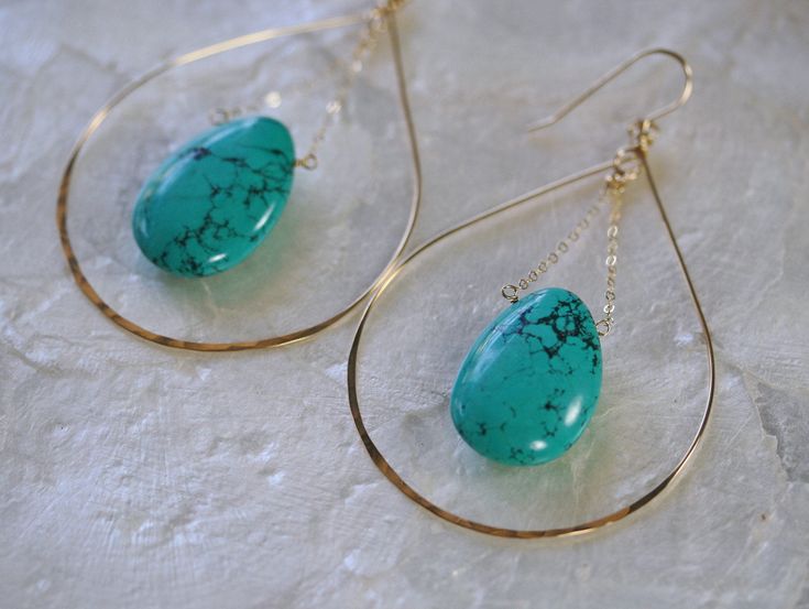 Large handcrafted gold hoop earrings fashioned into a teardrop shape and accented with a bold Turquoise briolette in the center. These lovely statement earrings are handcrafted from 14k gold filled metal, shaped and hammered for shine and texture. The teardrop shape highlights the bold Turquoise gemstone that hangs in the center for a one of a kind statement look. Earring Length 3.5 inches Earring Width at the base 2 inches Threaded Turquoise Necklace: http://www.etsy.com/listing/637197368 LINKS Turquoise Wire Wrapped Hoop Earrings Gift, Turquoise Hoop Jewelry Wire Wrapped, Turquoise Hoop Gemstone Jewelry, Turquoise Teardrop Pierced Jewelry, Pierced Turquoise Teardrop Jewelry, Turquoise Gemstone Hoop Jewelry, Turquoise Teardrop Pierced Earrings, Turquoise Hoop Pierced Earrings, Nickel-free Teardrop Turquoise Hoop Earrings