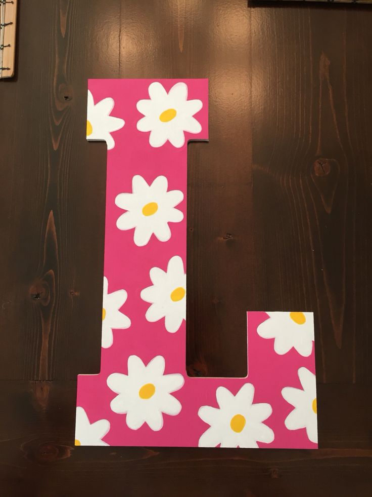 the letter l is decorated with white daisies and yellow centers on a pink background