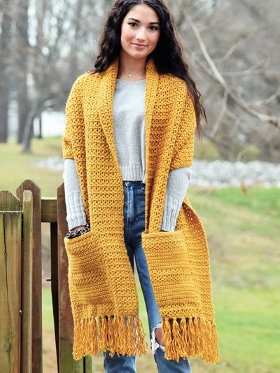 a woman wearing a yellow shawl and jeans