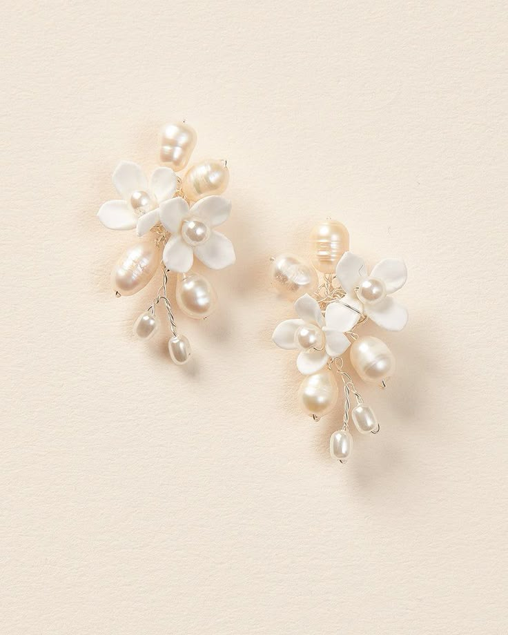 two pairs of pearl and crystal flower clip on earrings, one with white flowers in the middle