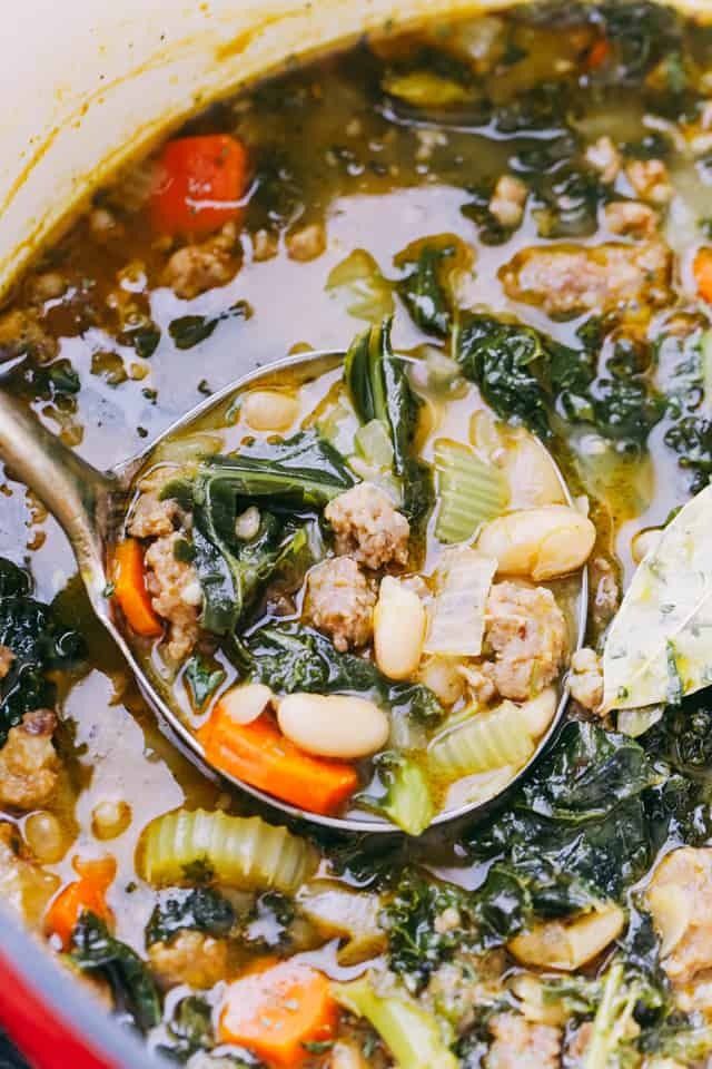 a ladle full of soup with meat and vegetables