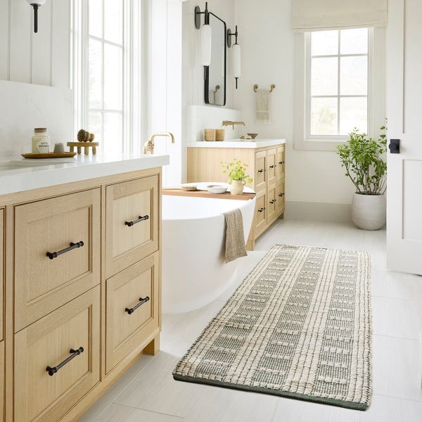 a large bathroom with white walls and wooden cabinets, along with a rug on the floor