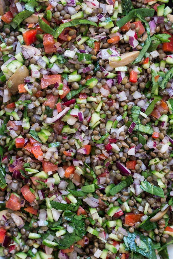 a salad with lentils, tomatoes, cucumbers and green onions in it