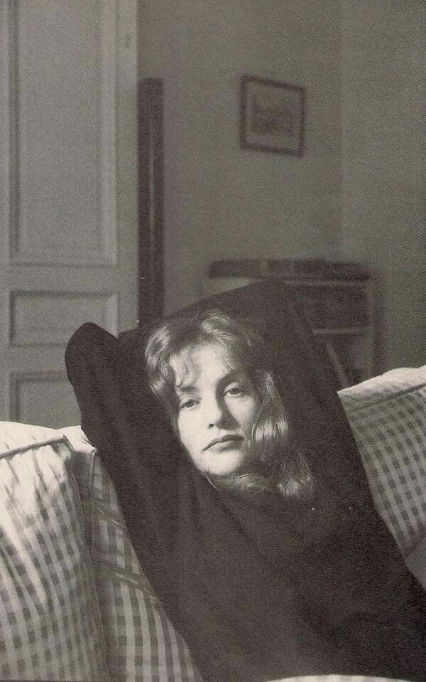 black and white photograph of a woman laying on a couch with her head under the covers