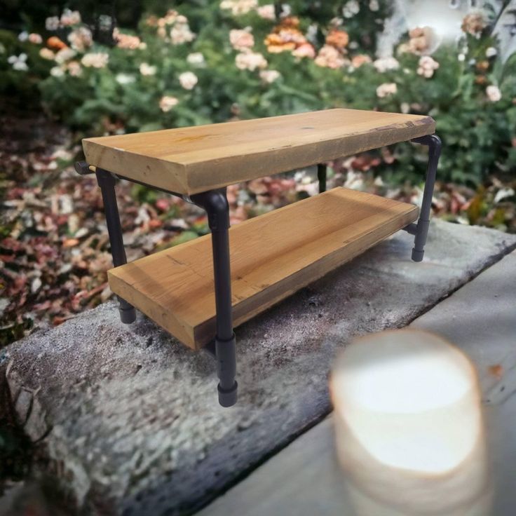 a wooden shelf sitting on top of a cement slab next to a lit candle and flowers