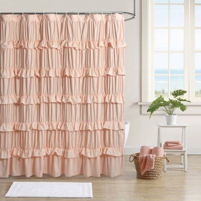 a pink shower curtain with ruffles on it in front of a white bath tub