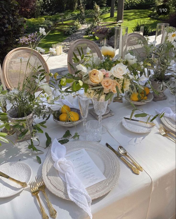 the table is set with plates, silverware and floral centerpieces on it