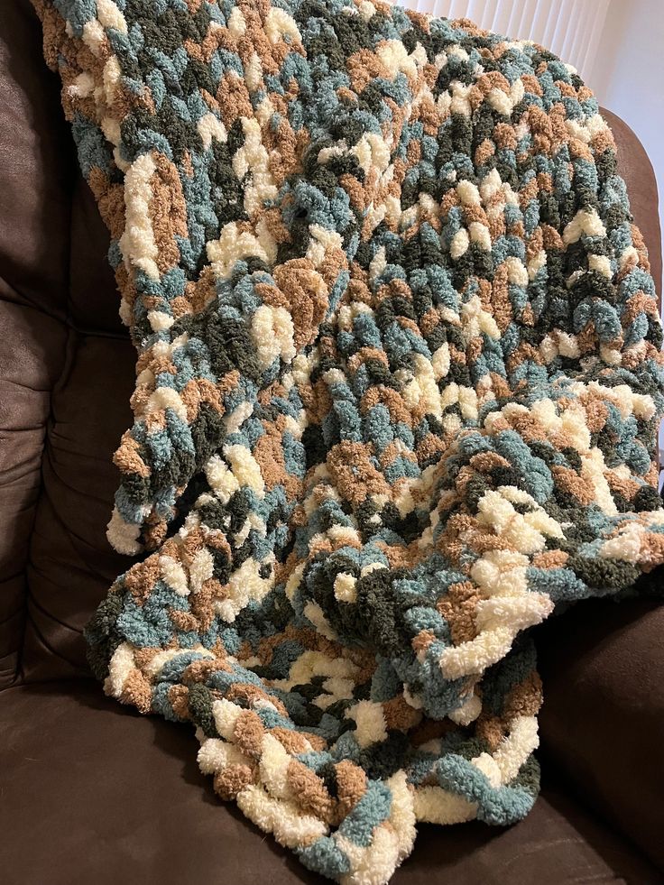 a crocheted blanket sitting on top of a brown couch