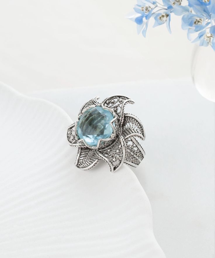 Blue Topaz Silver Sun Floral Victorian Ring, 925 Sterling Silver Artisan Handmade Women Filigree Ornate Ring, Women Fancy Flower Jewelry gothic goth ring, blue cocktail ring, november stone ring, anniversary gift, handmade flower ring, bold statement ring Material: 925 Sterling Silver (NICKEL FREE) Gemstone: Sky Blue Topaz 12 mm. -The birthstone of December and November, the tranquil azure color of a blue topaz ring can evoke thoughts of warm Caribbean seas on a cold winter day, and the stone given in celebration of the 4th and 19th anniversaries of marriage. Topaz is a symbol of love and affection, and has been said to be an aid to ones sweetness and disposition. Are you looking for a piece that symbolizes style and splendor? Well, look no further. Our Blue Topaz Silver Sun Floral Victori Vintage Flower Gemstone Jewelry, Vintage Flower-shaped Gemstone Jewelry, Blue Gemstone Flower Ring, Blue Flower-shaped Gemstone Ring, Silver Flower Ring With Birthstone, Elegant Silver Flower Ring With Birthstone, Blue Flower Gemstone Rings, Silver Flower Ring With Center Stone, Flower-shaped Wedding Jewelry With Gemstone Accents