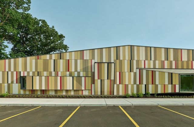 an empty parking lot in front of a multi - colored building with vertical striped walls