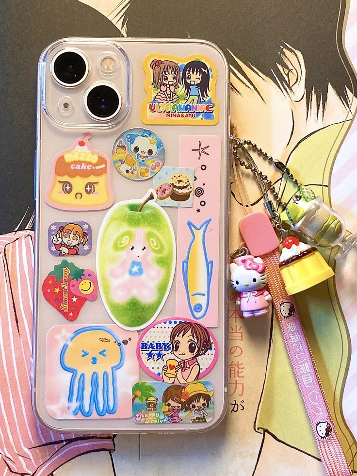 an iphone case with stickers on it sitting next to a pink ribbon and other items