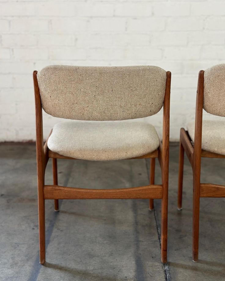 two chairs sitting side by side in front of a white brick wall and cement floor