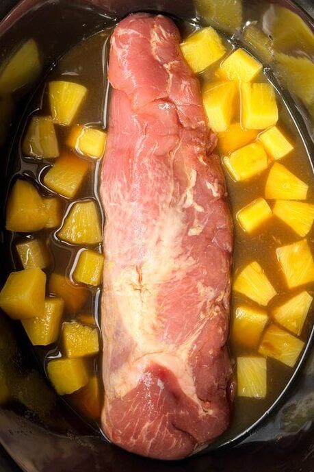 meat and vegetables in a slow cooker ready to be cooked