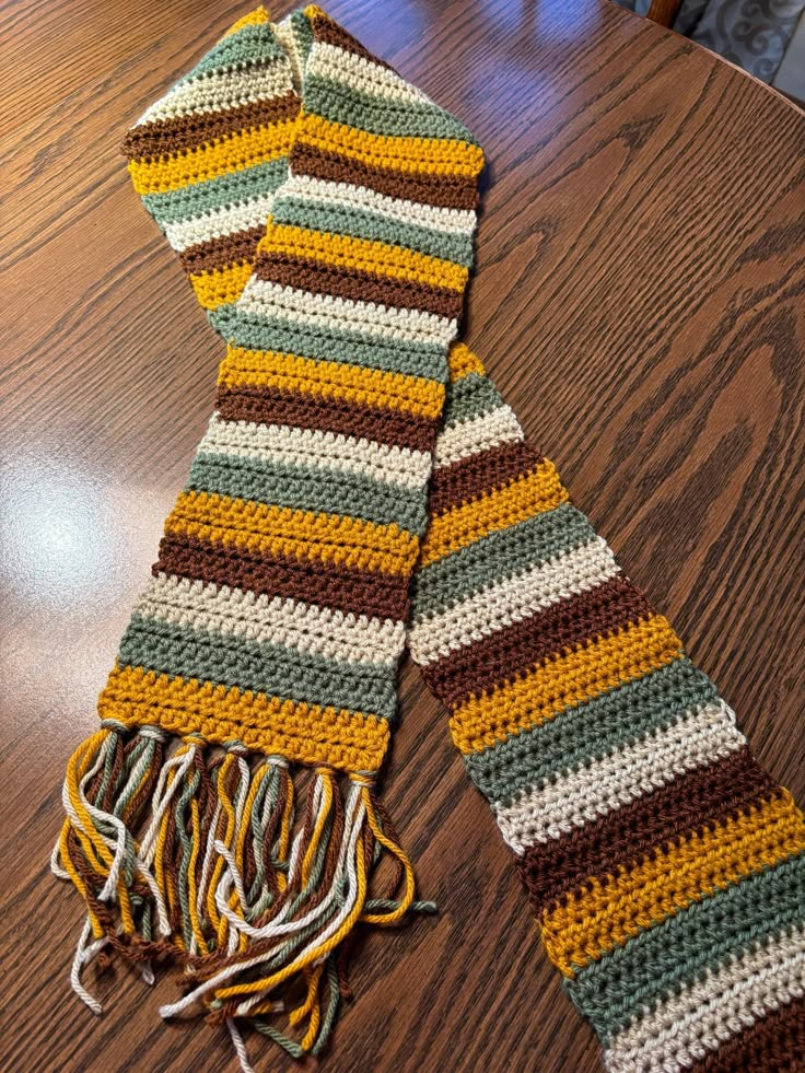 two crocheted scarfs sitting on top of a wooden table