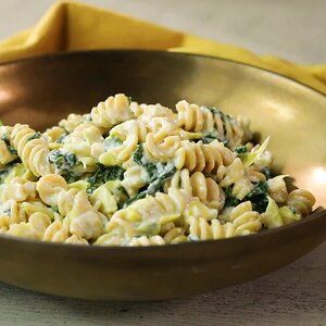 a bowl filled with pasta and spinach on top of a table