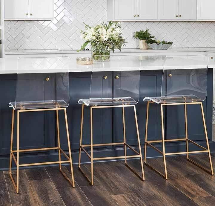 two clear bar stools sitting in front of an island