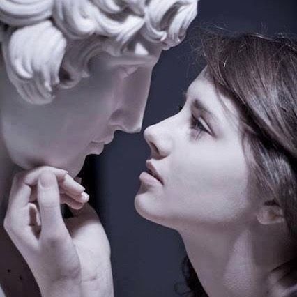 a woman is touching the face of a statue with her hand and nose to each other