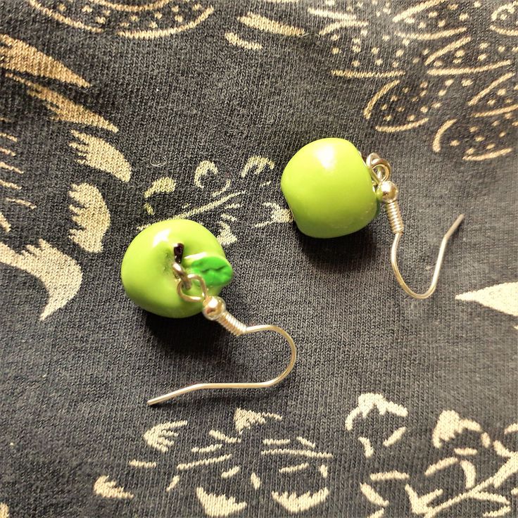 Cute and original dangle fruit earrings.   Kawaii green apple earrings  Hypoallergenic drop earrings.  Resin apples and stainless steel hooks.  A very original gift for fruit lovers, for veggies and vegans. *Measures 1.2 x 1.4cms  Total drop length: 3cms  Weight: 1.9g each  These earrings are shipped in a cardboard box to secure you will receive them in perfect conditions. Please specify if you want them as a gift when you order  Cardboardbox and gift ribbon are handmade with recycled and sustai Cute Green Jewelry With Fruit Design, Green Playful Earrings, Playful Green Earrings With Ear Wire, Green Novelty Dangle Jewelry, Playful Green Drop Earrings, Green Dangle Novelty Jewelry, Cute Green Jewelry Gift, Fun Green Nickel-free Earrings, Cute Adjustable Green Earrings