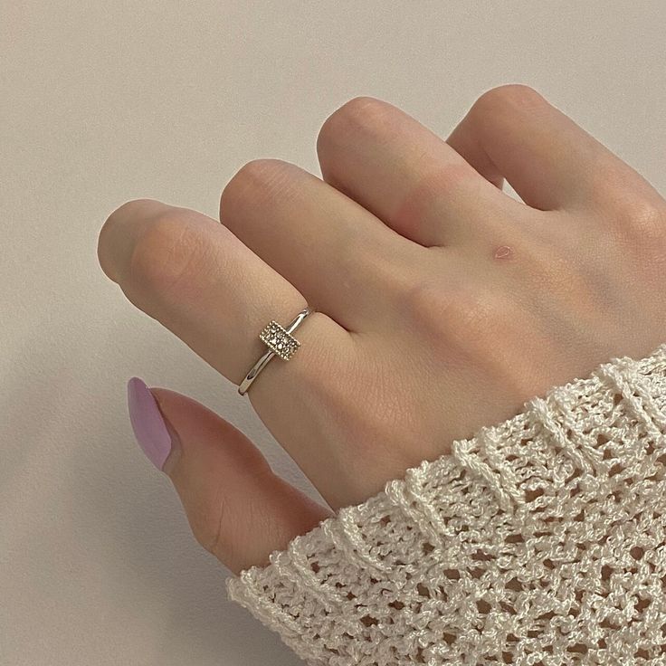 a woman's hand wearing a ring and sweater