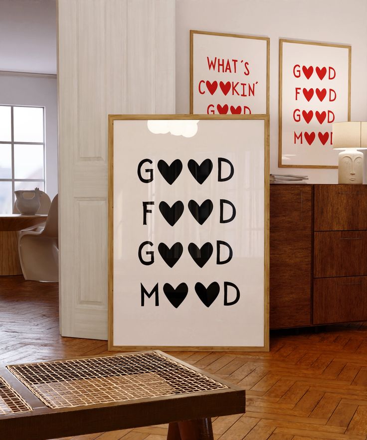 a couple of framed pictures sitting on top of a wooden floor next to a table