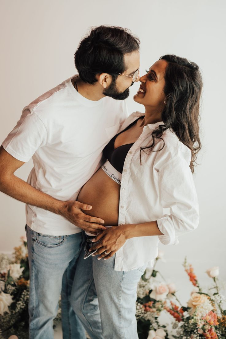 a man and woman standing next to each other in front of flowers with their mouths open