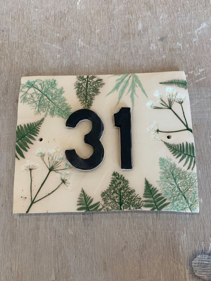 the number thirteen is made out of glass with green plants on it and black numbers