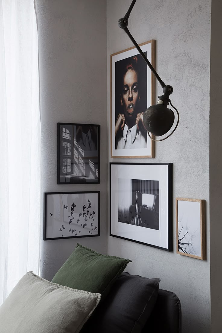 a living room with pictures on the wall and a lamp hanging from the ceiling above it