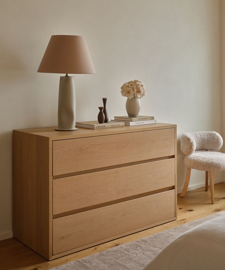 a bedroom scene with focus on the dresser and bed side table in the foreground