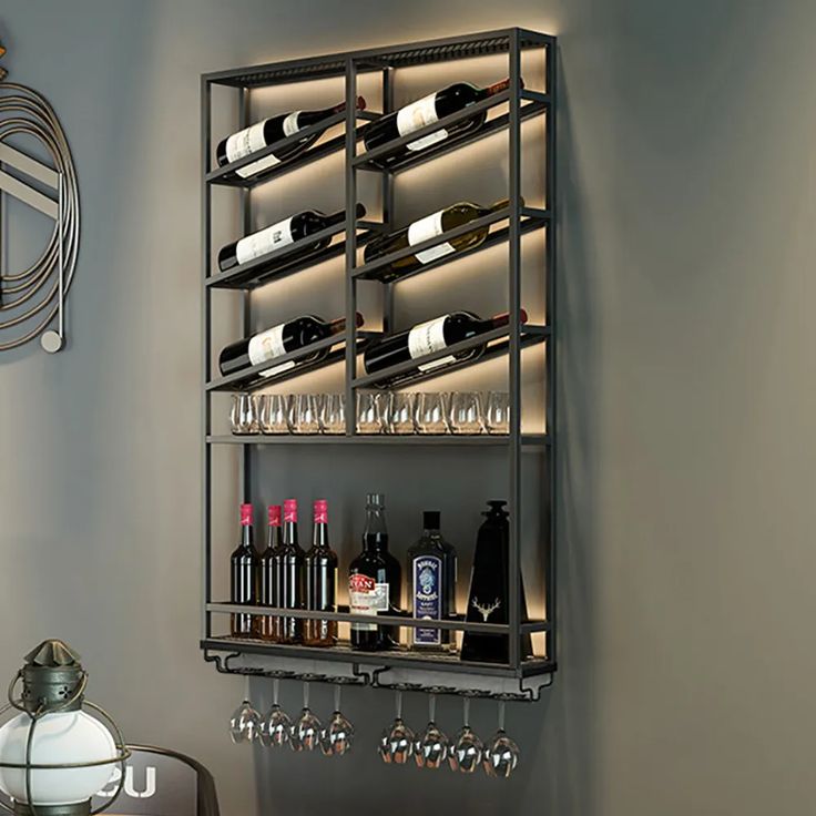 a wall mounted wine rack with many bottles and glasses on it next to a table