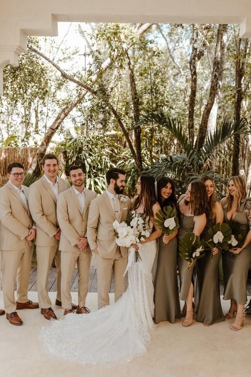 a group of people standing next to each other in front of some trees and bushes