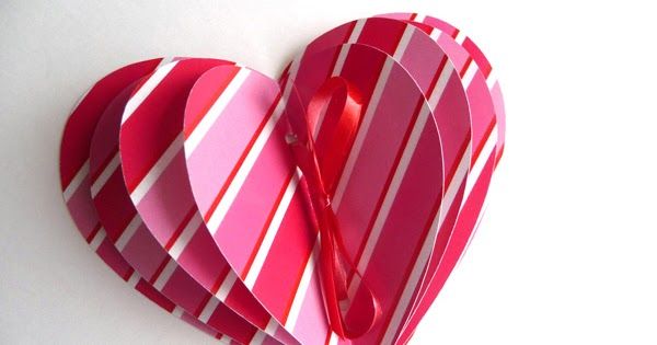 a heart shaped box with scissors in it on a white surface, cut out from strips of paper