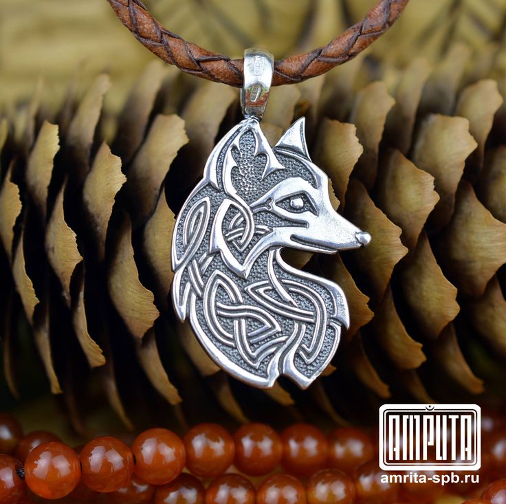 a silver wolf head on a brown leather cord necklace with beads and pine cones in the background