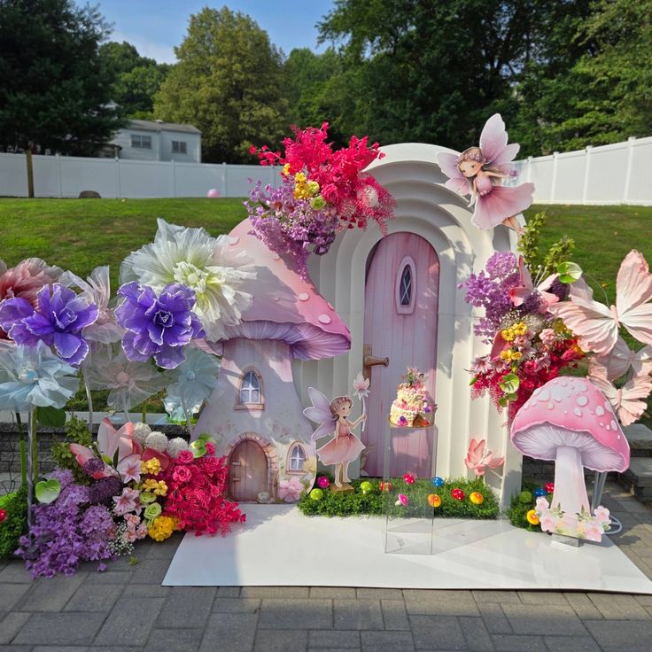 there is a fairy garden with pink and purple flowers on the ground in front of it