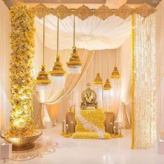 a white and yellow decorated stage with chandeliers, flowers and candles on the floor