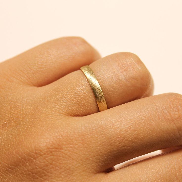 a person's hand with a gold ring on their left hand and the other hand holding it