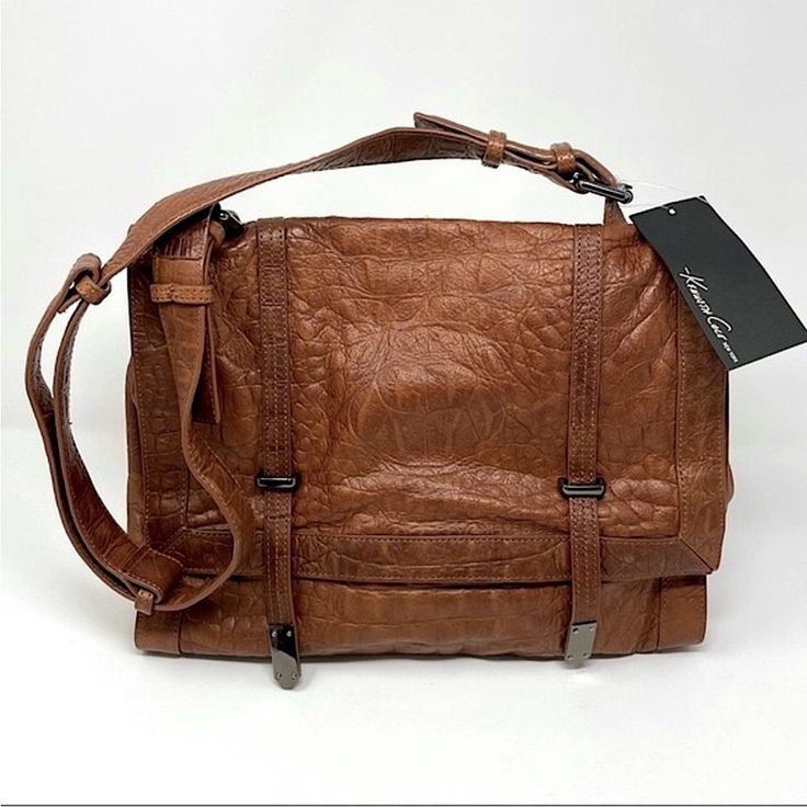 Kenneth Cole New York Leather Messenger Bag New With Tags Unisex Women Men Adjustable Strap Crossbody Or Shoulder Magnetic Snap Closure On Front Flap & Back Outer Pocket Zipper Pocket Inside Key Ring Attached Inside Cell Phone, Open Pockets Inside Small Loose Stitch In Seam On Bottom Of Bag. Some Color Variation In The Natural Leather Leather Smoke-Free And Pet-Free Kenneth Cole Messenger Bag Cognac Cognac Textured Leather Shoulder Satchel, Brown Flap Satchel With Magnetic Closure, Brown Satchel With Magnetic Closure And Flap Shape, Designer Brown Soft Leather Flap Bag, Designer Brown Leather Flap Bag, Designer Brown Flap Bag For Everyday, Brown Leather Satchel With Magnetic Closure, Brown Textured Leather Crossbody Flap Bag, Cognac Travel Bag With Magnetic Closure