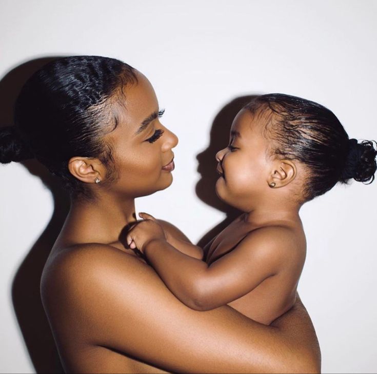 a woman holding a baby in her arms and looking into the distance with both hands