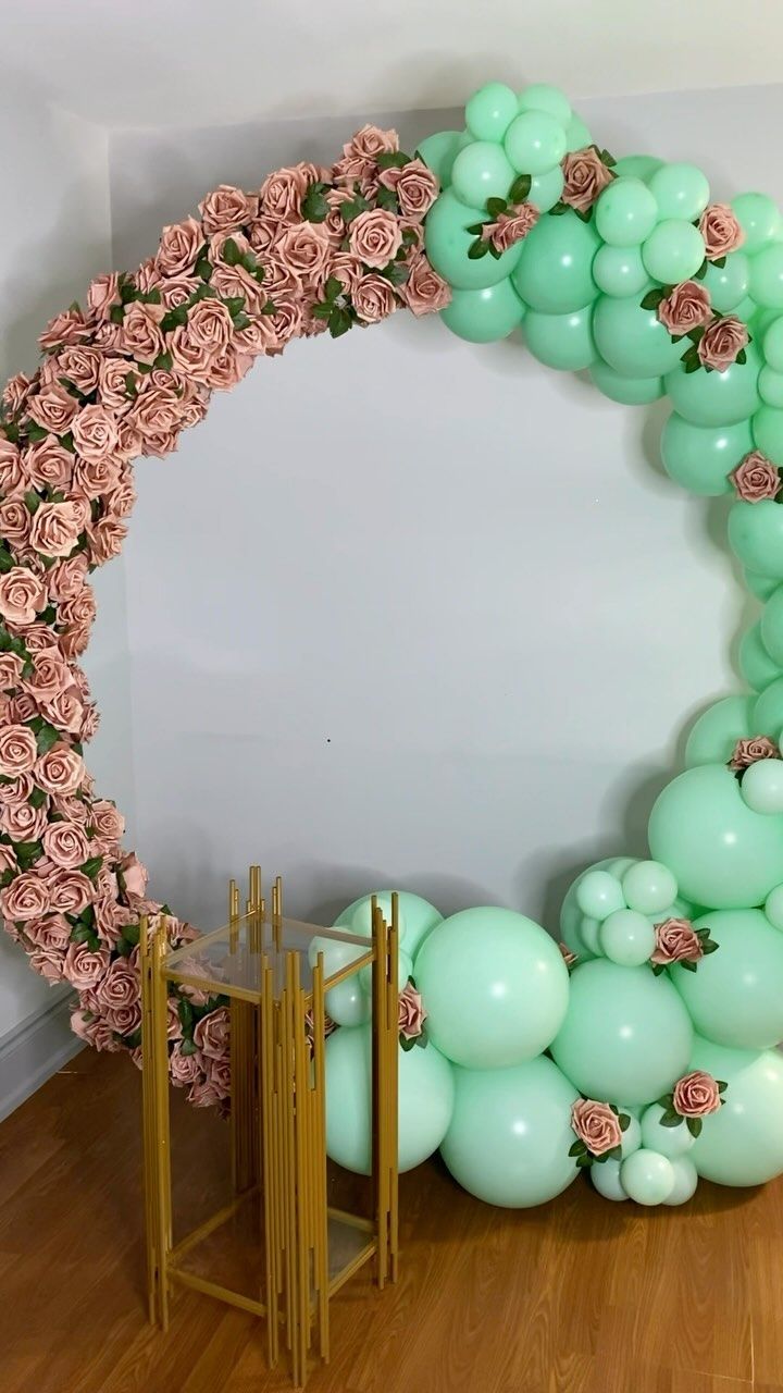 the balloon arch is decorated with roses and green balloons