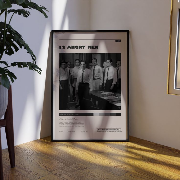 a framed poster on the wall next to a potted plant and wooden flooring