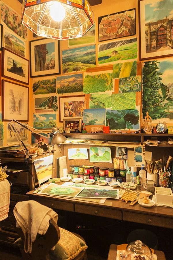 an art studio with lots of paintings on the walls and artwork hanging from the ceiling