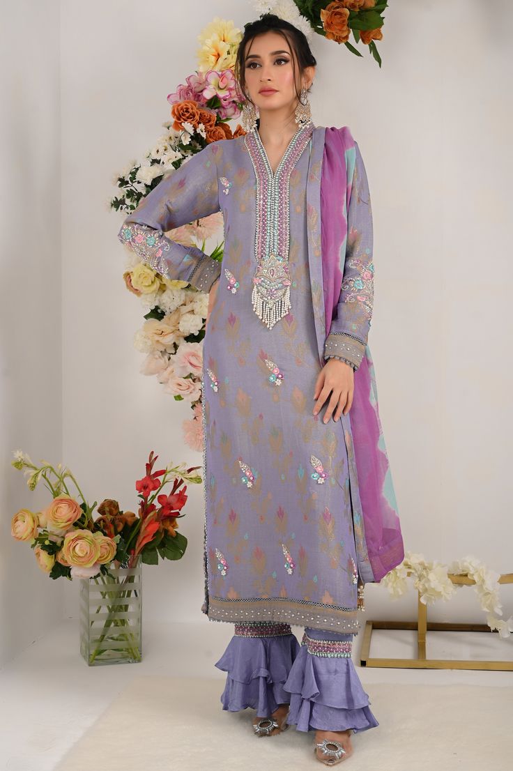 Divine into regal perfection with regal lilac blue. This lilac blue marvel boasts a neckline adorned with vibrant resham, beads and sparkle of sitara, delicately enhanced with beautifully curated bunch on neck line, sleeves and back as well, floral motifs on all over shirt front and intricate resham embroidey and lace work on shirts hem.to complete this ethereal ensemble it is paired with ombre dyed dupatta and two tier ruffled trouser. Shirt Fabric: Pure jacquard maysuri Shirt Length: 48” Pant Elegant Semi-stitched Purple Sets, Elegant Purple Salwar Kameez With Zari Work, Elegant Purple Set With Zari Work, Elegant Purple Sets With Zari Work, Elegant Purple Sets For Diwali, Elegant Purple Salwar Kameez For Eid, Elegant Purple Sets With Dabka Work, Elegant Purple Sets With Resham Embroidery, Purple Silk Kurta For Party