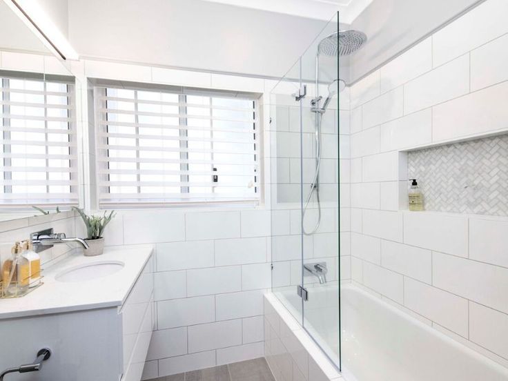 a bathroom with white tile walls and flooring next to a bathtub, sink, and shower