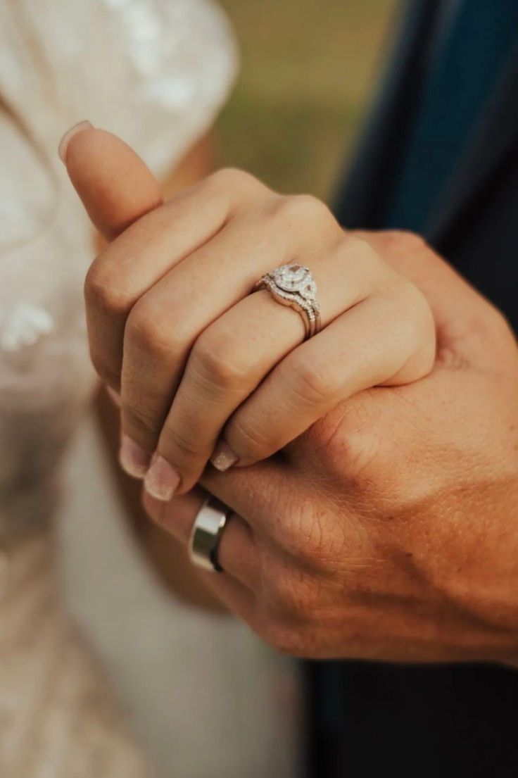 a man and woman holding hands while wearing wedding rings