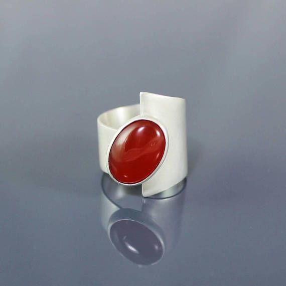 Modern Ruby Wedding Ring, Modern Sterling Silver Ruby Wedding Ring, Modern Cabochon Ring For Anniversary, Modern Cabochon Rings For Weddings, Modern Ruby Ring For Formal Occasions, Modern Bypass Ring For Anniversary, Modernist Oval Gemstone Rings, Oval Gemstone Rings In Modernist Style, Contemporary Wide Band Jewelry Gift