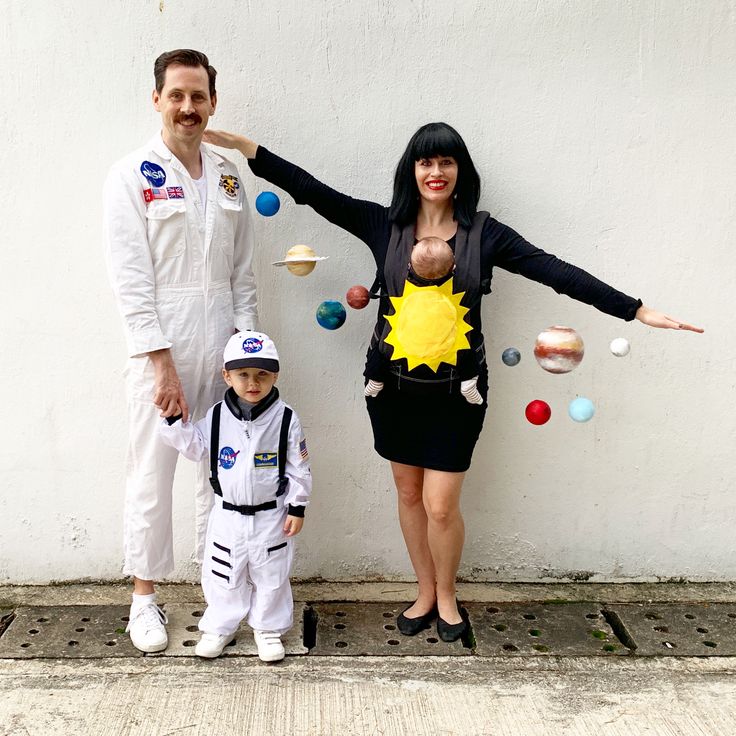 a man and woman standing next to a small child in space suits with planets around them